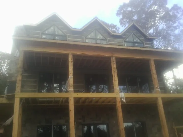 Dormers and porch framing on a large log home under construction — Roof Coating work by our crew in Pineland