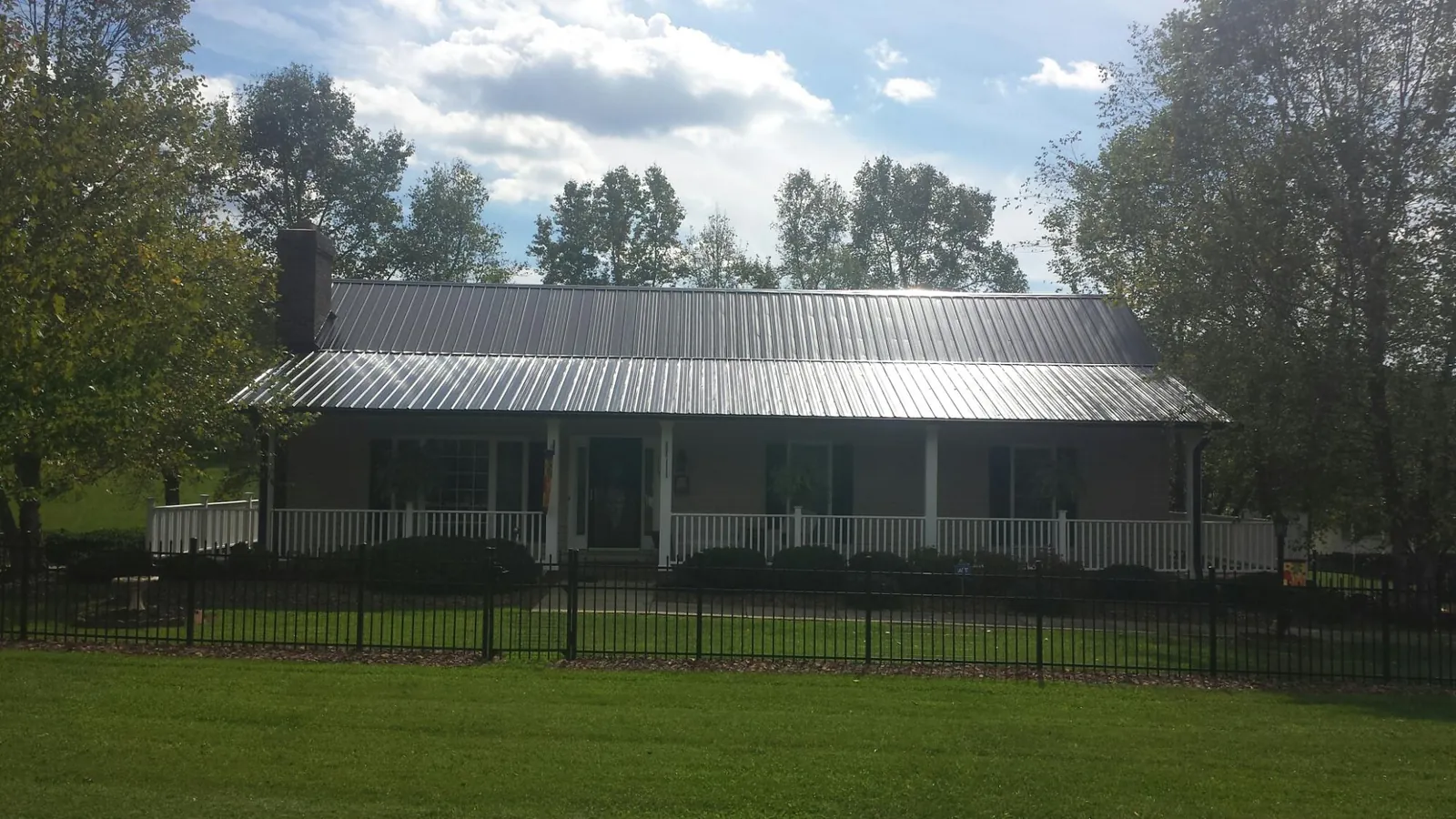 Gray metal roof on a brick ranch with a full width front porch — Gutter Guard Installation work by our crew in Pineland