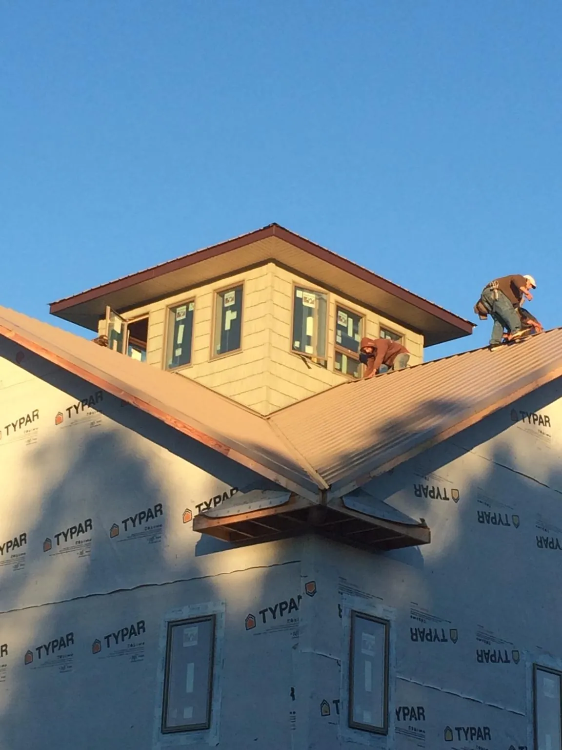 Roofers working around a rooftop cupola on a new metal roof at sunset — Roof Waterproofing in Pineland by Roofing Brothers